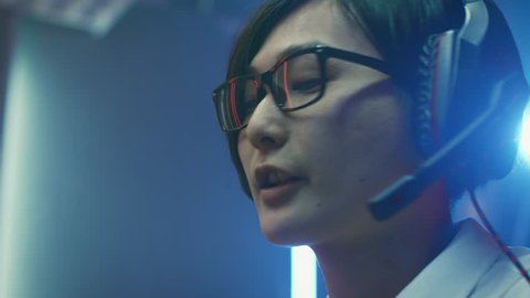 Close-up Portrait of the Professional Gamer Playing in Online Video Game, He's wearing Glasses, talks/ chats with His Teammates / Friends through Headphones. Shot on RED EPIC-W 8K Helium Cinema Camera
