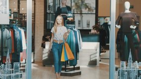 Pretty blonde go out from shop with sales at shopping mall