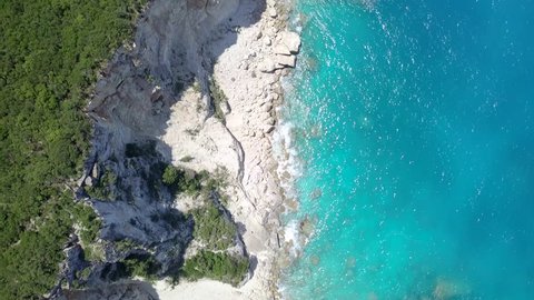 4k aerial top down view moving forward over mediterranean coastline cliff edge with white sand and turquoise sea