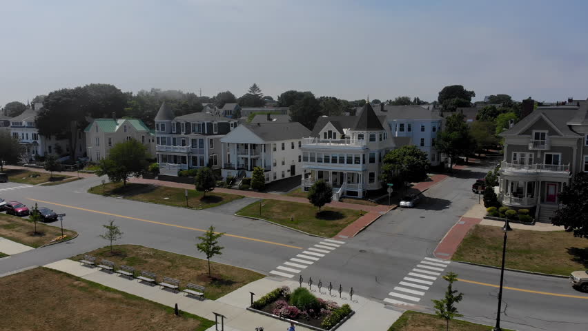 A daytime aerial establishing shot of upscale victorian-style homes in Portland, Maine as the fog rolls in.  	