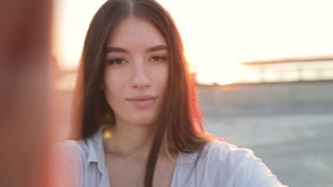 Young smiling woman holding camera showing tongue in sun beams, slow motion