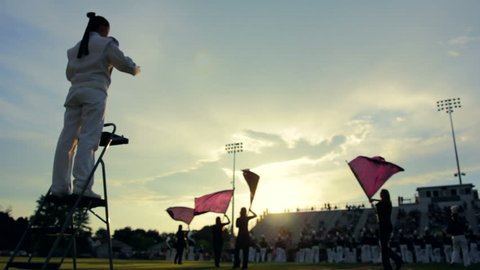 Marching band preforming before a high school football game as the sun sets