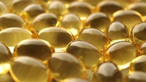 Omega 3 gold fish oil capsules, rotation background, macro