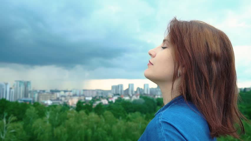 happy woman dreaming while standing on top of the mountain. young woman breathes fresh mountain air. woman portrait, relaxation concept. Young woman on the background of a distant big city. Fusion Royalty-Free Stock Footage #1013916983