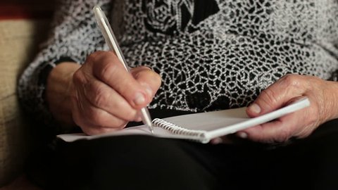 Old woman writing something in notebook