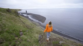 Young woman arms outstretched at Hvitserkur basalt stack along the eastern shore of the Vatnsnes peninsula, in northwest Iceland. People travel lifestyles concept