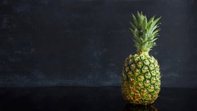     Stop motion ripe tropical fruit pineapple on a black background. Time lapse food loop footage 