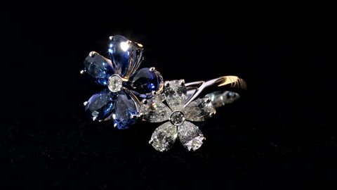 Close-up shot of two sparkling,shining white and blue flower shaped ring with diamonds and saphire jewelery.