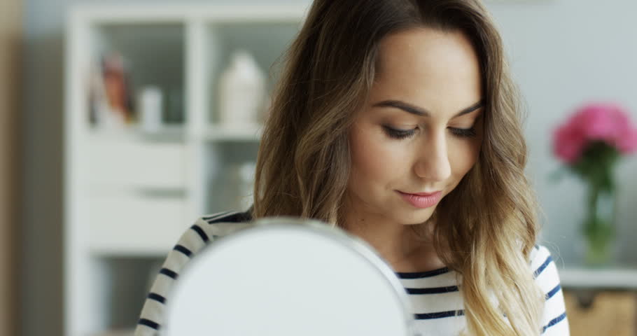 Close up of the charming youg woman doing makeup for herself as being beauty blogger. Indoors.