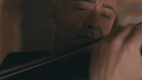 Extreme close up shot of a male violinist playing the violin in a string quartet