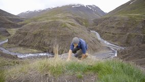 Young man hiking, pulls out hand to reach the one of teammate. A helping hand to reach the mountain top. Hiker assists teammate to reach mountain top above canyon in Iceland