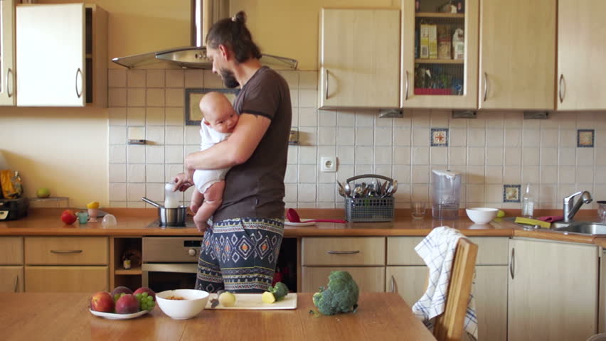 A successful young father feeds the baby in the kitchen. Baby care, bottle feeding. Father's Day Royalty-Free Stock Footage #1013954876