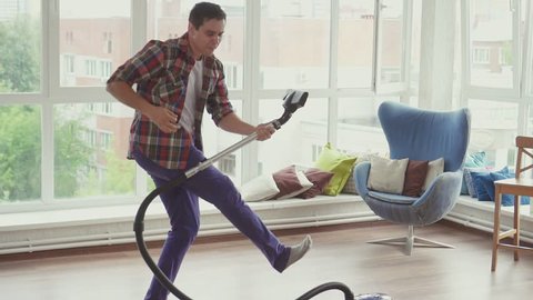 Man doing the cleaning vacuums and have fun dancing.Slow mo