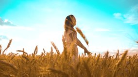 girl is walking along the wheat field nature slow motion video. beautiful girl in white dress running hands to the side on field at sunset nature freedom happiness light and the blue sky. girl wheat