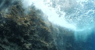 underwater scenery of rock splash foam and waves on surface
