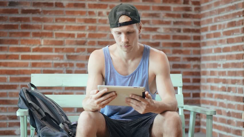 Student at a bus stop reading a news line.
