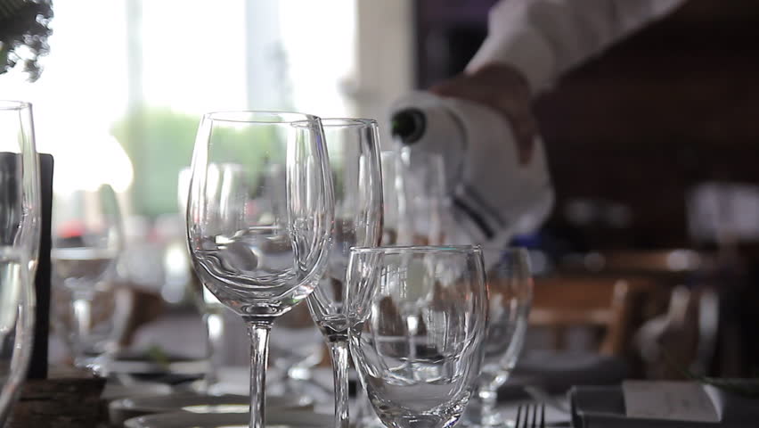 Pouring champagne into 2 drinking glasses slider close up 