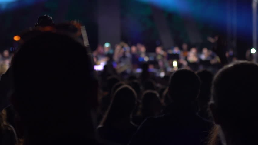 People enjoying the concert of a philharmonic orchestra performing popular songs in the open, in the city park. Slow motion, 25p/100fps