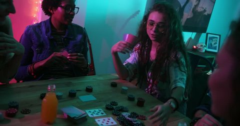 Young woman winning chips at poker card game while hanging out with friends at home