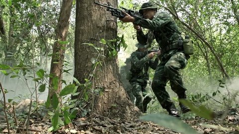 Soldiers walking and patrolling, ready to fire. Chinese army soldiers with green camouflage uniform in high grass tropical jungle walking. Modern warfare and combat concept.  Arkivvideo