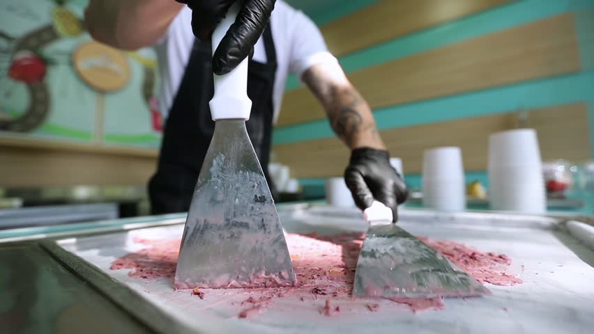 Stir-fried ice cream rolls at freeze pan. Rolled ice cream, hand made ice cream dessert. Fried ice cream machine with steel chilled pan.