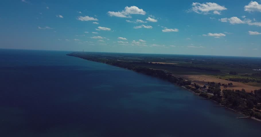 Peaceful drone flight down the shores of Lake Ontario in Olcott, NY. A large lighthouse appears in the distance. 