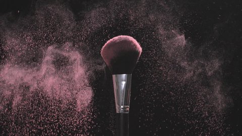 Two Make-up brushes with pink powder on a black background