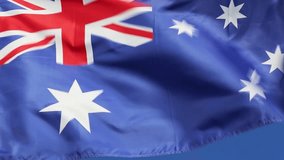 Australian national flag waving in wind front of blue sky. Flag of Australia natural video.