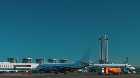 The planes are standing at the airport waiting for their turn to take off. Around the cars of technical airport services