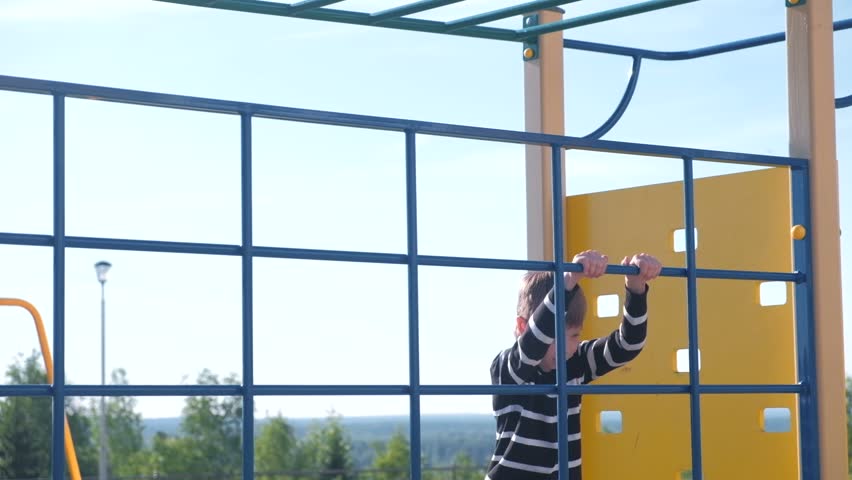 Boy climbs on a climbing wall holding the rope on the Playground. Royalty-Free Stock Footage #1013994500
