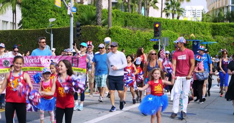 LOS ANGELES, CALIFORNIA, USA - JULY 4, 2018: Young kids with american flags marching at 4th of July Independence Day celebration parade in Santa Monica, Los Angeles, California, 4K