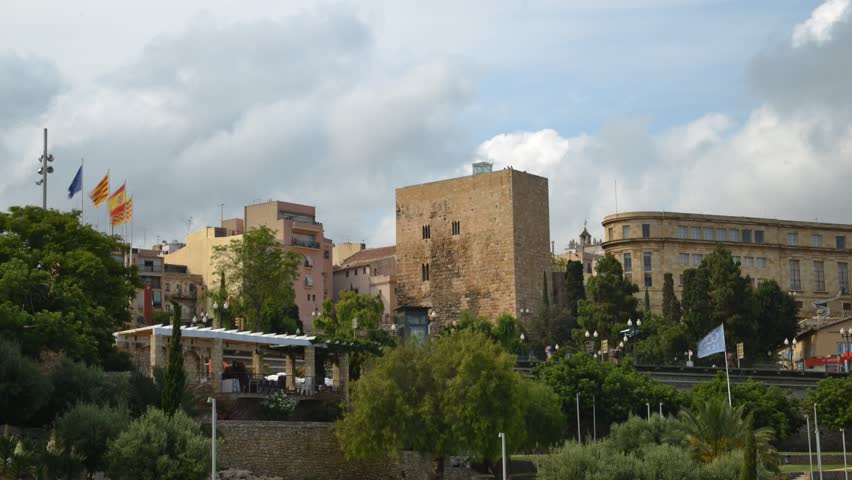 Time lapse at Placa de la UNESCO at entrance to historic town of Tarragona with signs pointing to major touristic landmarks.