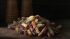 Dried colored fusilli pasta on wooden table