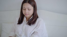 Young asian woman using smartphone on bed after wake up in morning for reading good news and social media. 