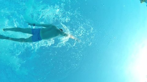 Underwater view of a male swimming in pool, view from below