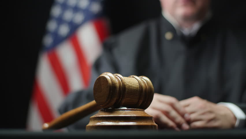 Judge's hand with wooden gavel hammering against American flag in United States court Royalty-Free Stock Footage #1014022817