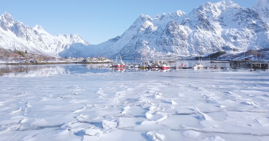 Aerial panorama drone view of beautiful Lofoten Islands winter scenery with traditional fishing boats lying in harbor on a cold sunny day with scenic blue sky, Norway, Scandinavia, northern Europe Royalty-Free Stock Footage #1014028415