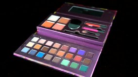 This point of view video shows a perspective view of a makeup brush application using a colorful makeup palette on black background.