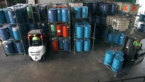 Fork-Lift Carrying 3 Barrels Passing Through Shelves Filled With Barrils