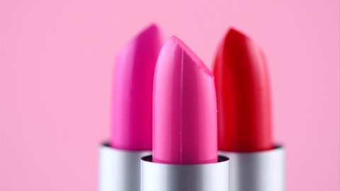 Lipstick. Fashion Colorful Lipsticks rotated over pink background. Lipstick tints palette, Professional Makeup and Beauty. Beautiful Make-up concept. Lipgloss. Lipsticks closeup. UHD 4K video