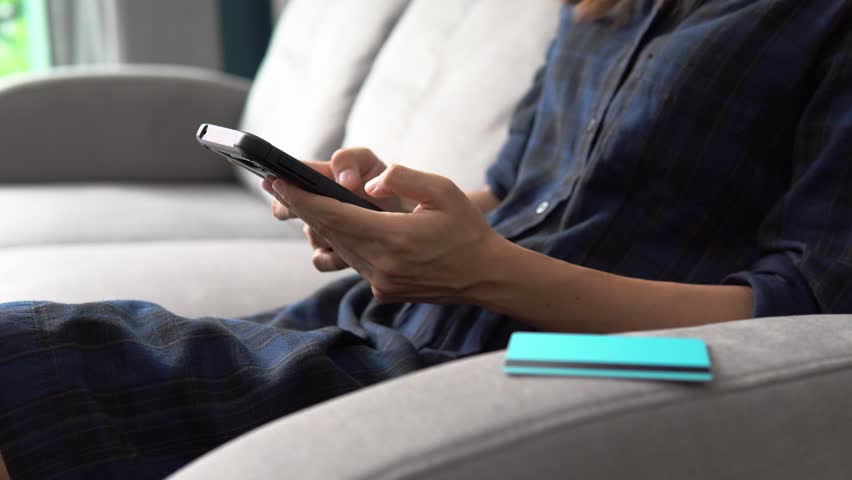 Young woman holding a credit card and using smartphone for online shopping
