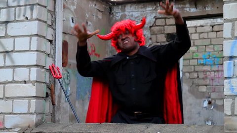 Devil rapper.  Funny afro america man  in fancy dress of devil is dancingand rapping. Carnival, dance, humor