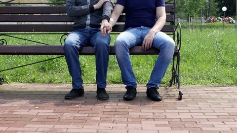 A man sits on a bench to him comes and another man sits down and strokes his leg, homosexuality, harassment