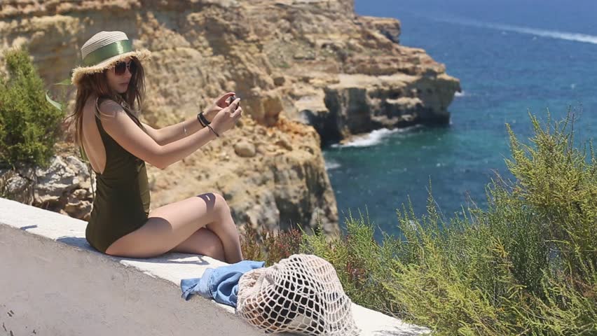A pretty girl on the ocean makes a selfie