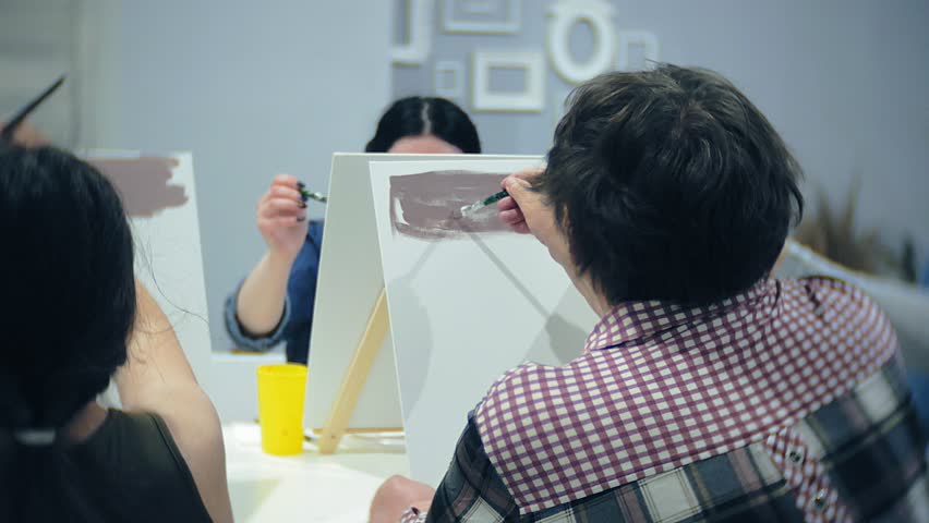 art school, creativity and people concept - group of students with easels, paintbrushes and palettes painting still life at studio, old and young people draw 4k