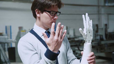 Robotic hand repeating the moves of young scientist's hand. Medacal hand prothesis 4K