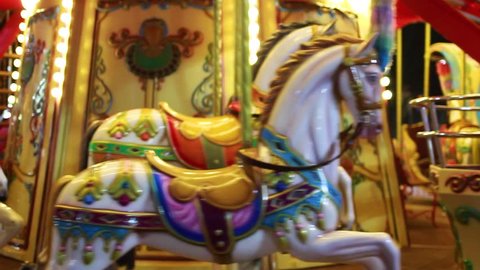 Bright red and golden carousel with horses and bright glowing lights turning around without passengers in darkness of night. Real time full hd video footage.