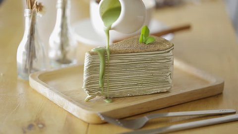 Cutting Green tea crepe cake with knife on wooden plate.: film stockowy