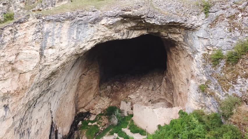 Flying around a huge entrance to a cave system in a middle of a forest. Royalty-Free Stock Footage #1014060818