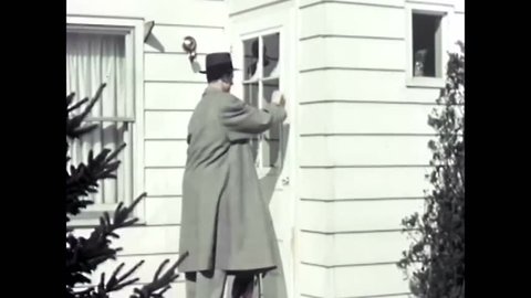 CIRCA 1950s - A door-to-door salesman demonstrates a vacuum cleaner for a housewife in the living room of her home.